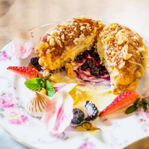 Fried ice cream dessert with berries, strawberries, mint, and edible flowers on a floral plate.