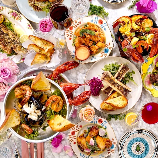 An overhead view of a lavish dinner spread with various seafood, meats, and drinks on a marble table.