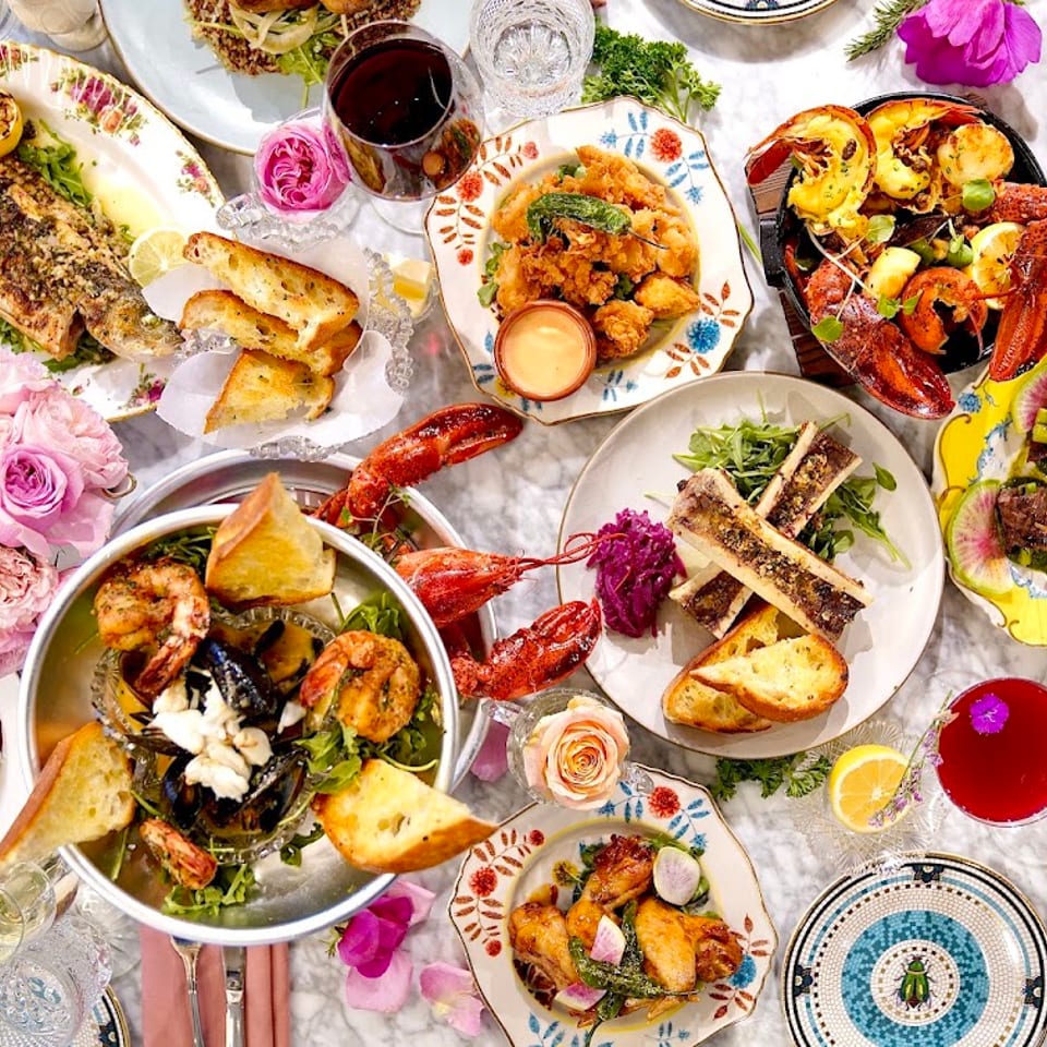 An overhead view of a lavish dinner spread with various seafood, meats, and drinks on a marble table.